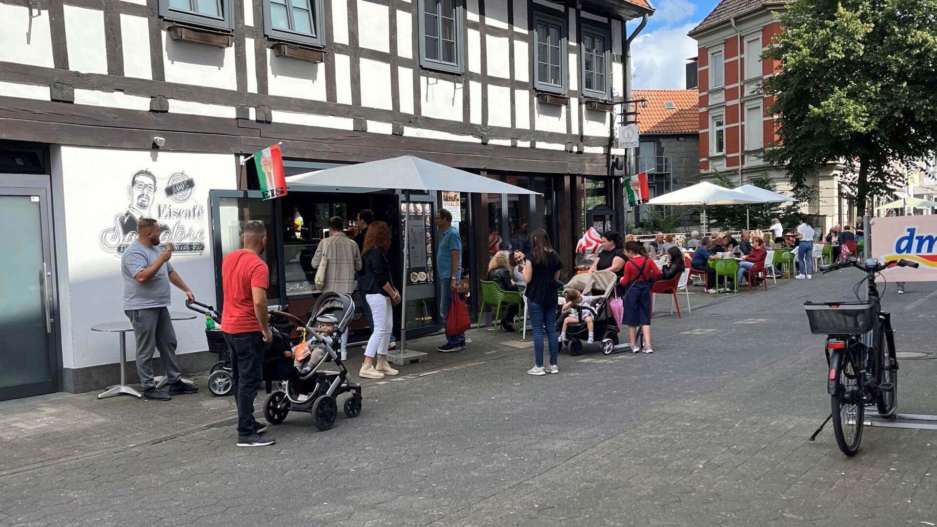 Mehrere Menschen mit Kinderwagen und lockerer Stimmung vor einem Restaurant mit Fachwerkfassade